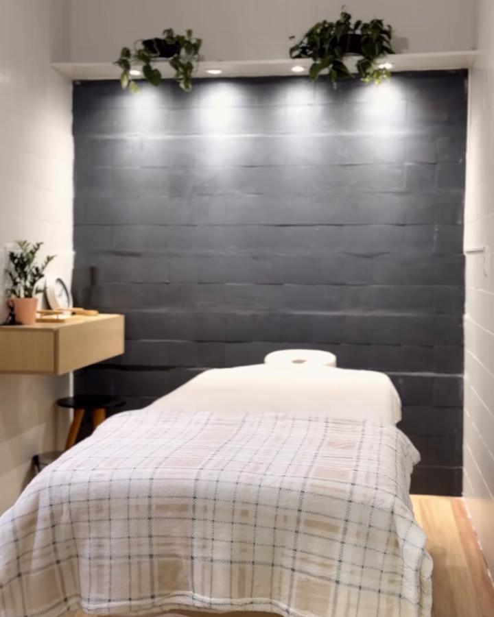 Sala de terapias manuais com maca, parede escura e iluminação baixa