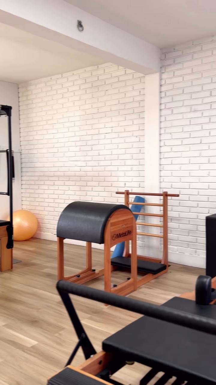 Barrel e reformer de madeira junto à janela da sala de Pilates